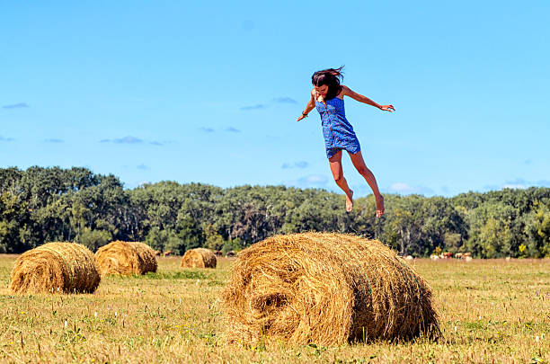 istock Young woman jumps on haystack in a field. Her hands 610745030