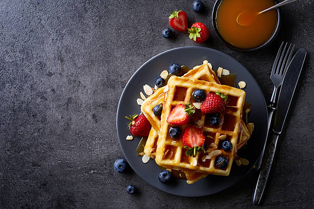 Plate of belgian waffles Plate of belgian waffles with caramel sauce and strawberries on dark gray background. From top view belgian culture photos stock pictures, royalty-free photos & images