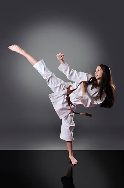 bella giovane cintura marrone karate femminile facendo calcio - extreme sports karate sport exercising foto e immagini stock