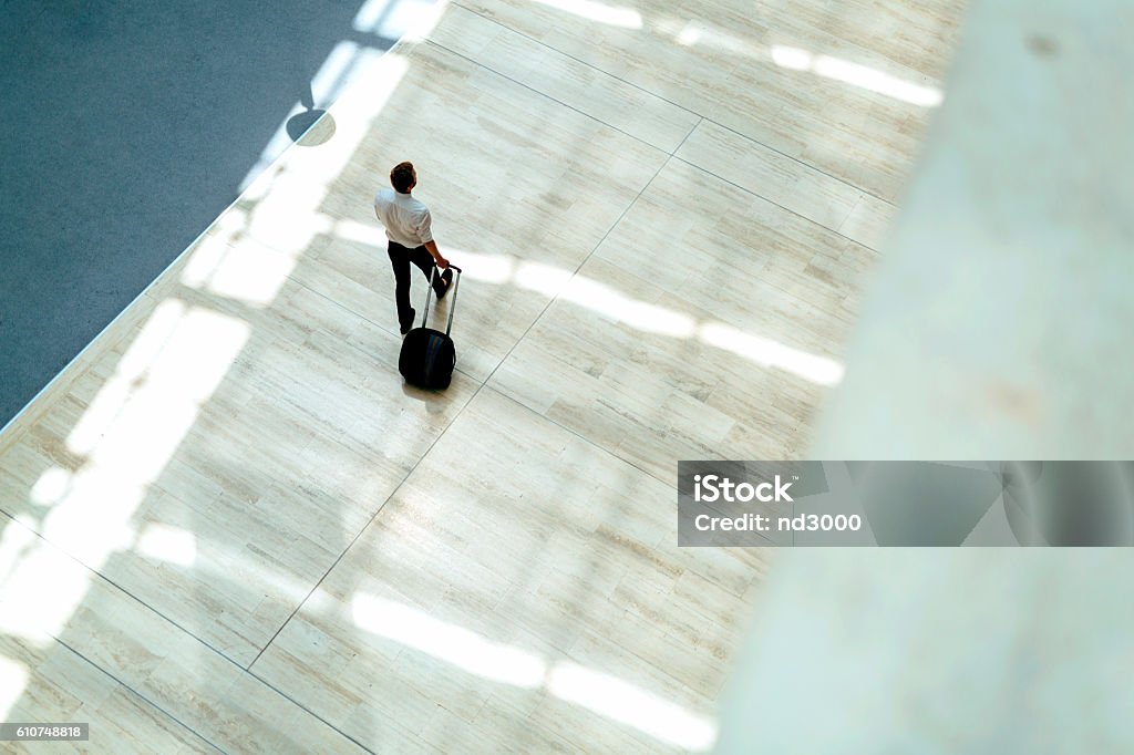 Handsome business holding a trolley Handsome business holding a trolley and walking in a modern building seen from above Business Travel Stock Photo