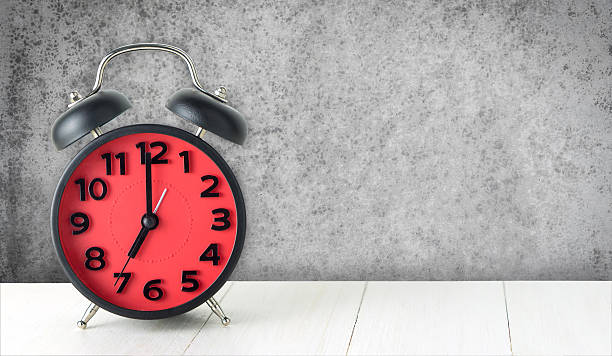 istock Red Alarm clock on white table with concrete wall 610749318