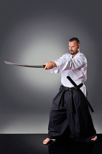 istock Handsome young black belt male karate posing with sword 610750762
