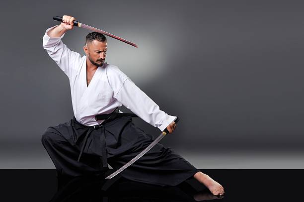 istock Handsome young black belt male karate posing with swords 610750850