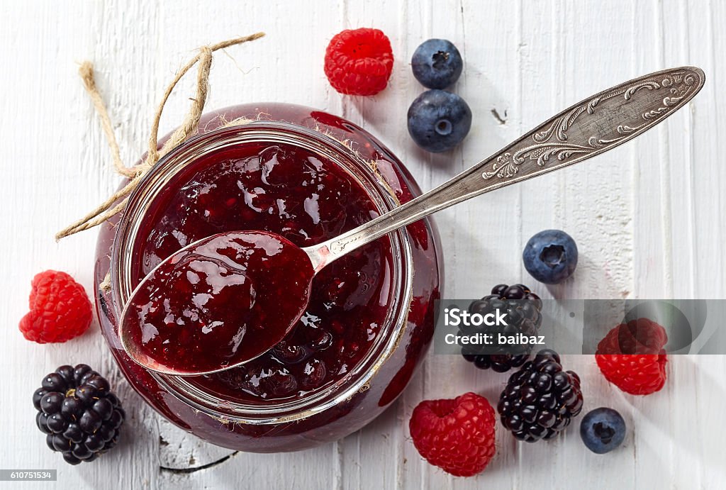 Jar of wild berry jam Jar of wild berry jam on white wooden background from top view Preserves Stock Photo