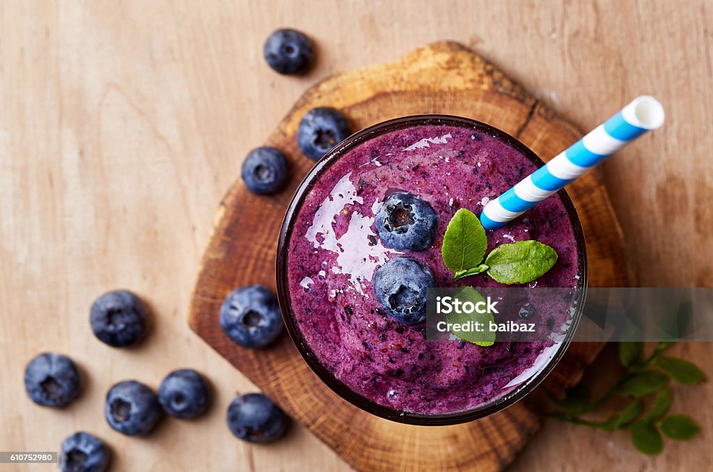 Glass of blueberry smoothie Glass of blueberry smoothie on wooden background from top view Smoothie Stock Photo