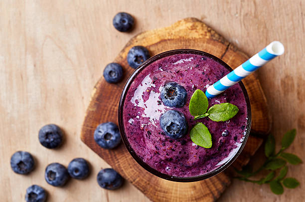 Glass of blueberry smoothie Glass of blueberry smoothie on wooden background from top view blueberry stock pictures, royalty-free photos & images