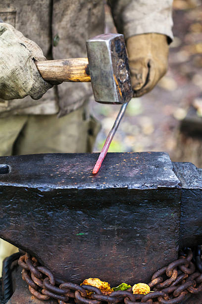 istock Blacksmith forges hot steel rod with sledgehammer 610757082
