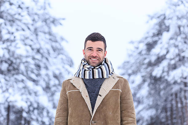 istock Smiling young man standing in snow forest 610757842