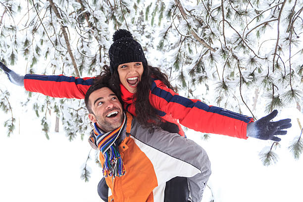 istock Young couple having fun in piggyback ride in snow forest 610762586