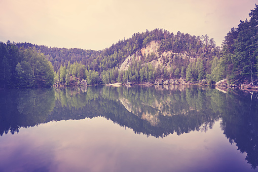 Vintage toned serene mountain lake with reflection in calm water.