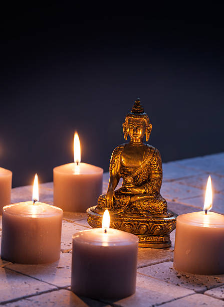 istock bronze Buddha with warm lighted candles for concept of mindfulness 610765598