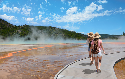 Girls wearing hats hiking on vacation. Beautiful Grand Prismatic Spring at Yellowstone National Park.