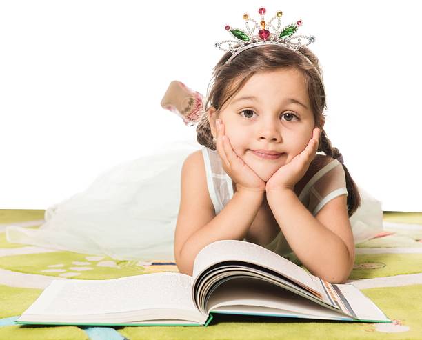 little adorable girl with princess costume reads fairytale book.