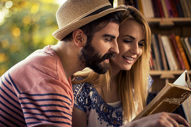 istock Young and happy couple reading same book in nature 610769914