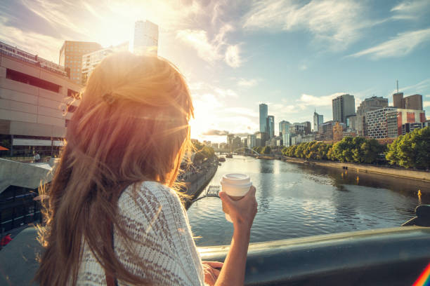 Caucasian female enjoys city life in Melbourne Cheerful young woman in Melbourne on a bridge overlooks the Melbourne CBD along the Yarra River on a beautiful day. Australia. yarra river stock pictures, royalty-free photos & images