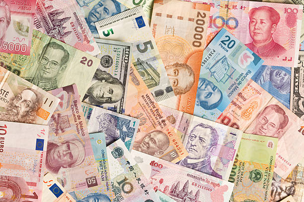 International Currency Global Money Exchange and Business Finance A colorful variation and collection of international currency, a global business money exchange and finance. Photographed in studio, at high angle in horizontal format. currency exchange stock pictures, royalty-free photos & images