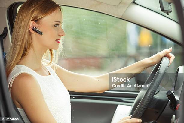 Mujer Conduciendo Coche Con Auriculares Foto de stock y más banco de imágenes de Manos libres - Manos libres, Auriculares - Aparato de información, Bluetooth
