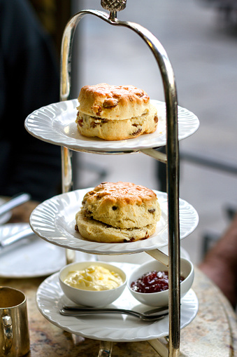 Fancy scones with clotted cream and jam for English style High Tea, shallow depth of field, focus on front of scone.  This image was taken in York, England at a fancy tea house.