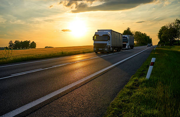 istock Two white trucks driving on the road at sunset. 610775684