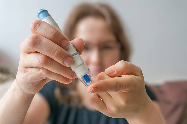 la mujer está usando la aguja para la prueba del nivel de glucosa con el glucómetro. - diabetes human pregnancy women blood sugar test fotografías e imágenes de stock