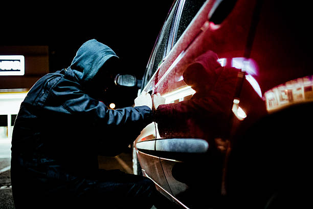 Man stealing a car Car thief  in action late at night, wearing a black mask on his head thief stock pictures, royalty-free photos & images