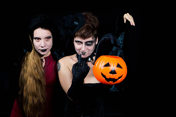 istock Two young make up women holding pumpkins, isolated on black 610783046