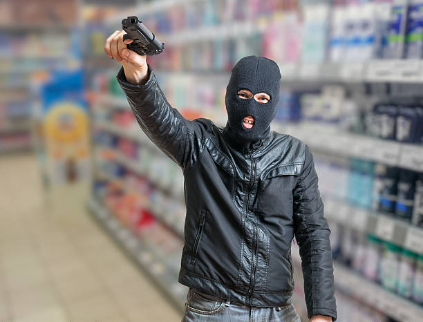 istock Robbery in store. Robber is threatening and aiming with pistol. 610838526