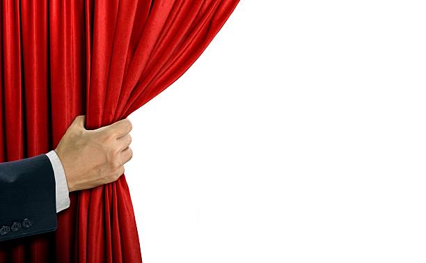 istock Hand opening stage red curtain over white 610838846