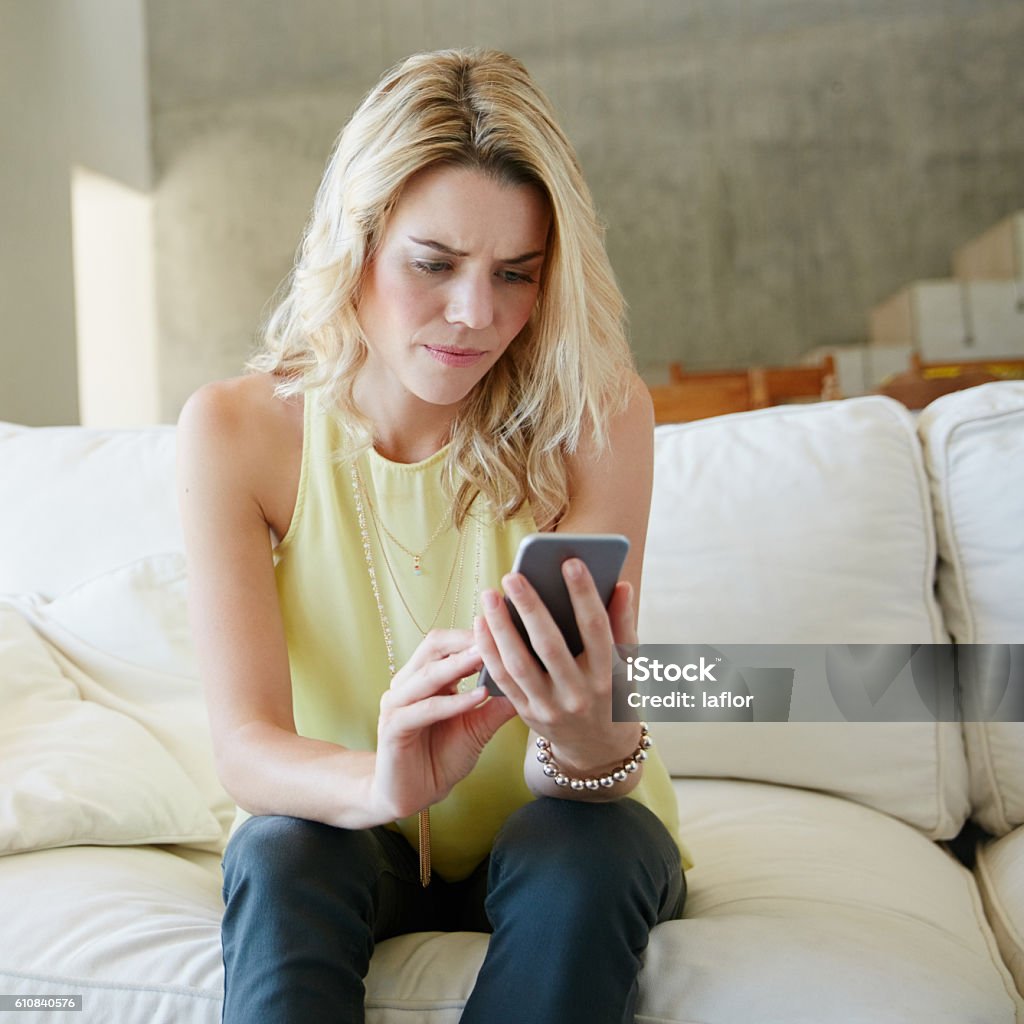 Not the news she was hoping for Shot of a stressed young woman looking at her phone at home Sofa Stock Photo
