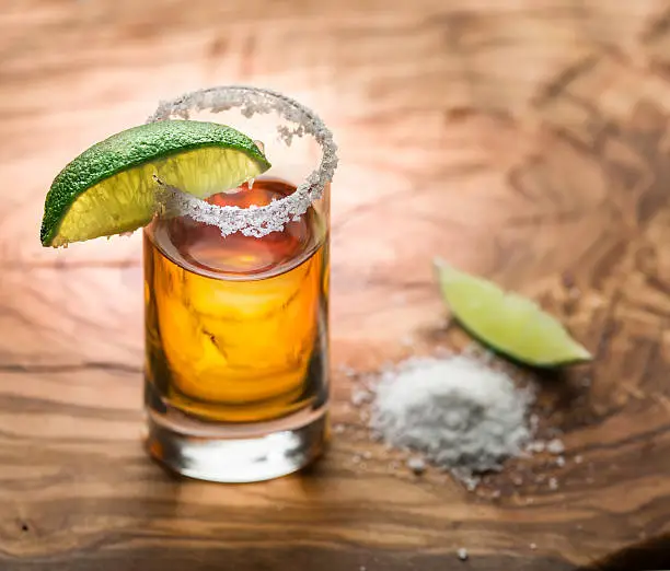 Photo of Single shot of tequila served with lime and salt.