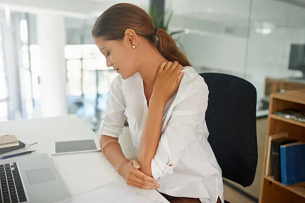 Shot of a young businesswoman experiencing neck and shoulder pain at work
