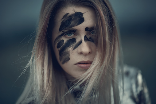 blond hair woman attitude with black makeup on her face, feeling agressive and serious.
