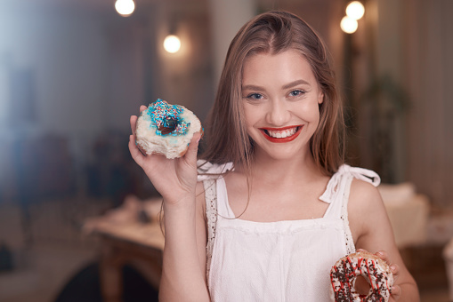 happy woman portrait holding donuts and smiling, enjoying having them and showing to the camera.