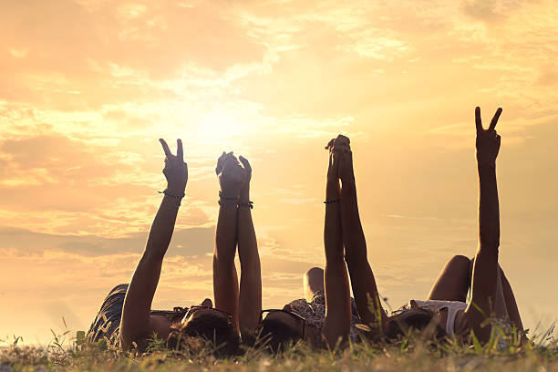women lying in the meadow raise their arms