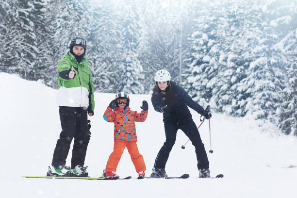 thumbs up for skiing family in winter day skyiing and enjoying the season, looking at camera and showing thumbs up. thumbs up for skiing stock pictures, royalty-free photos & images