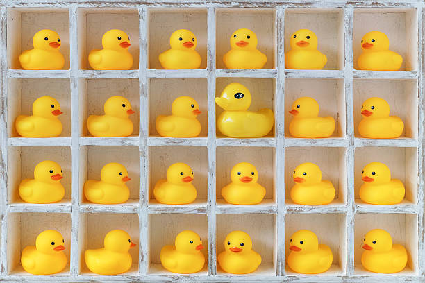 istock Small rubber ducks in pigeon holes, one alien duck. 610850100