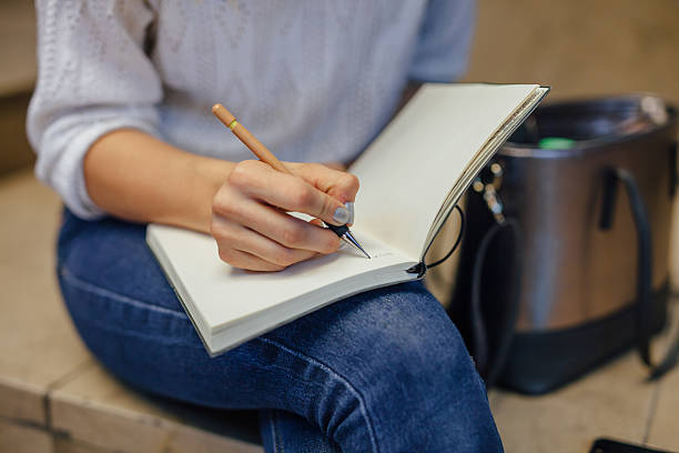 Woman's hand writing something at the notebook. Indoor stock photo