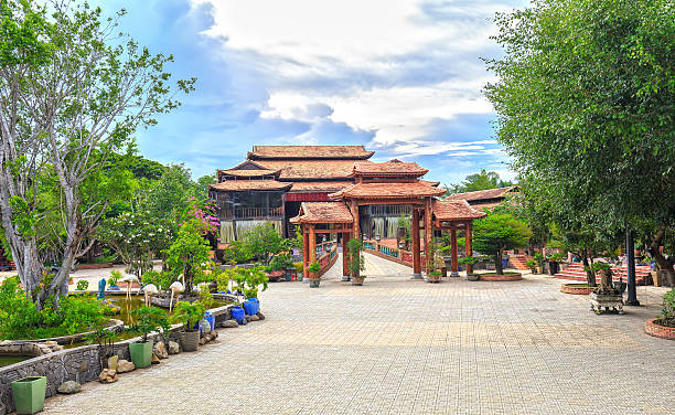 Long An, Vietnam - September 18th, 2016: Gate to old imperial house roof architecture with wooden columns honoring ancient definition on a hundred year existence in rural Vietnam