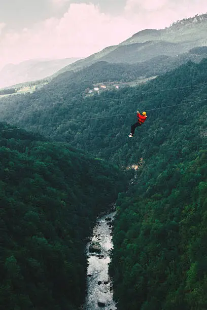 Man in red coat on zip line under the Tara river Gorge 