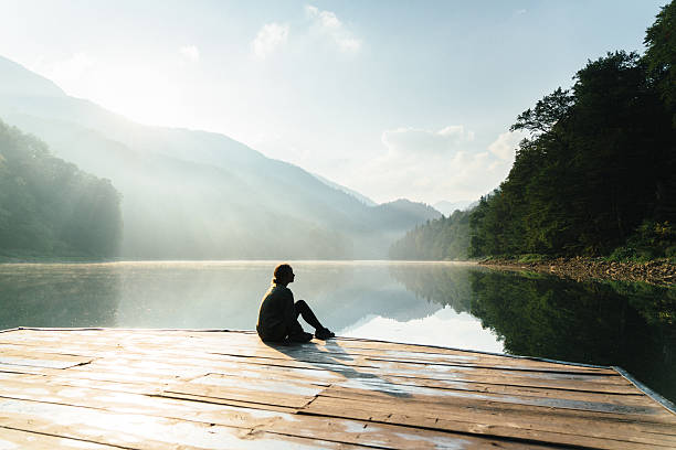 woman near the lake in mountains - wood tranquil scene serene people lake imagens e fotografias de stock