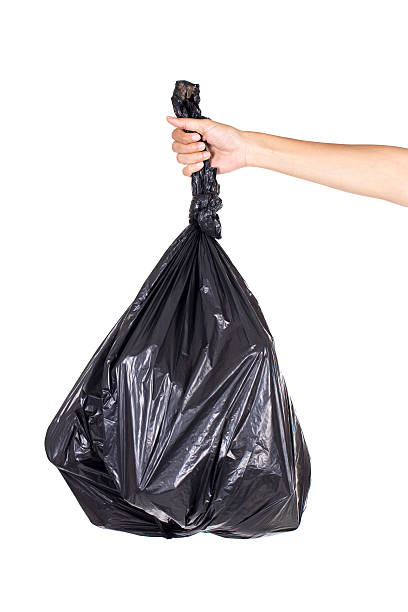 istock Hand holding black bag of rubbish on white background 610853434