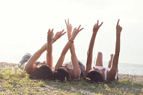 Photo of young women lying in the meadow raise their arms