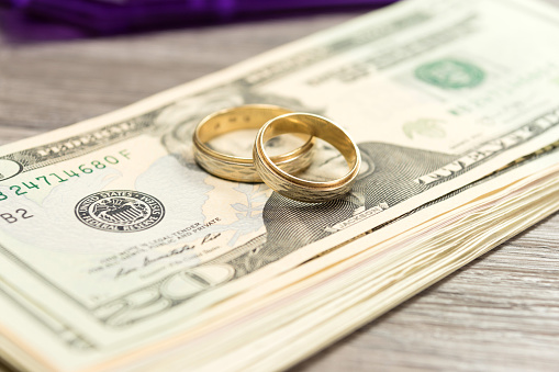Dollar banknotes and two golden wedding rings