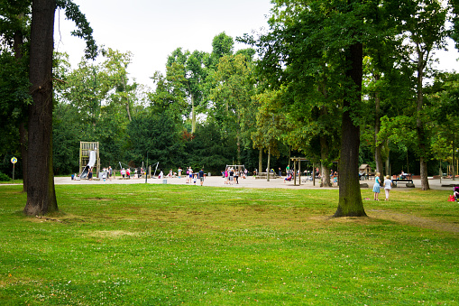 Düsseldorf, Germany - July 23, 2016: Capture of families on playground in park Hofgarten in Düsseldorf at summertime. People have several ethnicities.