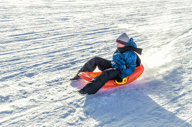 istock child comes down from the mountain riding a red sled 610862782
