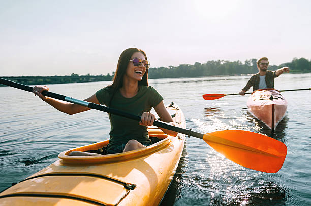 Couple kayaking together. Beautiful young couple kayaking on lake together and smiling people and lifestyle stock pictures, royalty-free photos & images