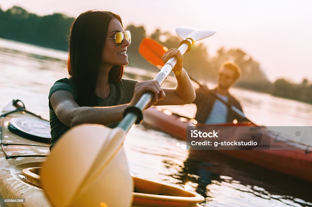Enjoying great time on river. Beautiful young couple kayaking on river together and smiling to you Kayaking Stock Photo