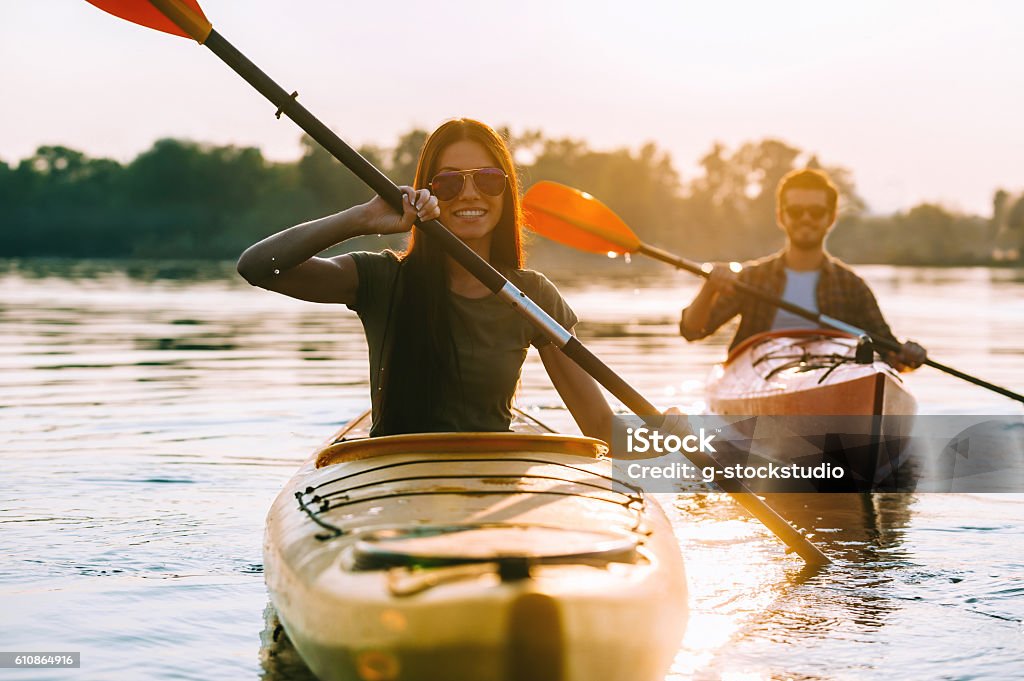Enjoying river adventure. Beautiful young couple kayaking on river together and smiling Kayaking Stock Photo