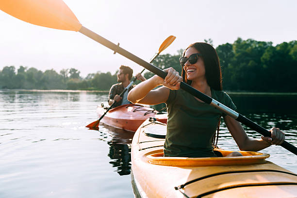 Nice day for kayaking. Beautiful young couple kayaking on lake together and smiling summer fun stock pictures, royalty-free photos & images