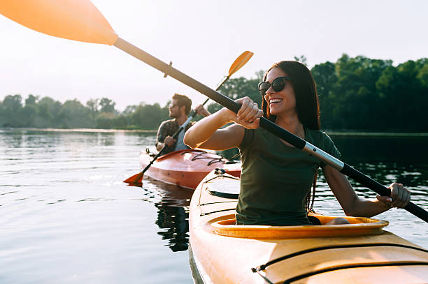 Nice day for kayaking. Beautiful young couple kayaking on lake together and smiling enjoyment stock pictures, royalty-free photos & images